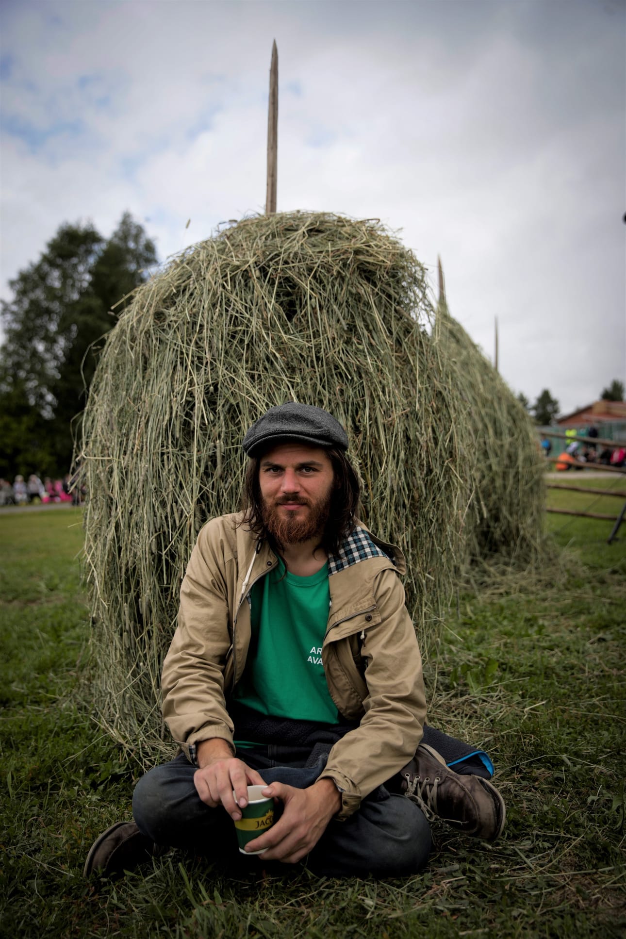 Tuomas Kokkonen juhla-alueella heinäseipään edessä. Herättäjäjuhlien maalaisromanttisissa koristeluissa oli myös kukka-asetelmia ja maitotonkkia.