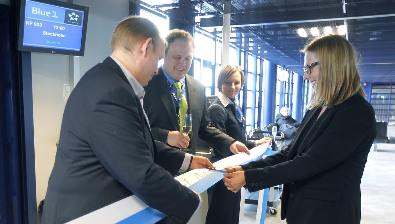 Niina Pitkäkari Matkatoimisto Areasta leikkasi virallisen nauhan reitin avajaisissa. Blue1:n viestintäpäällikön Jari Suvan (vas.) ja myyntipäällikön Tuomas Kankaalan avustuksella.