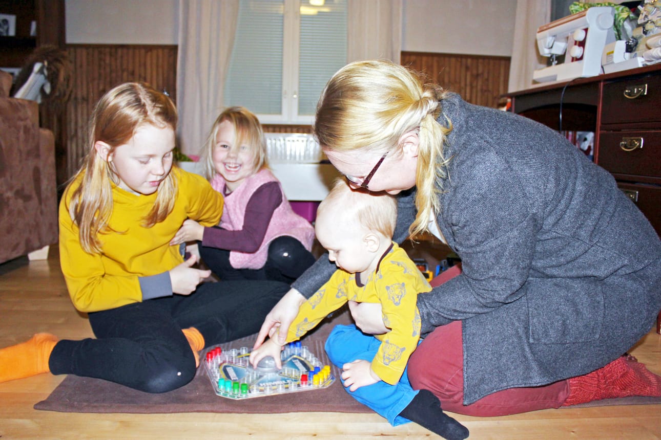 Oik: Pikku-Vennikin jo opettelee Kimblen pelaamista. Äiti opettaa, pelikavereina Aada ja Lotta.