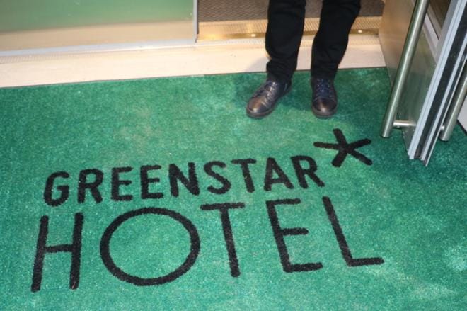 Vieraat astuvat vihreältä matolta hotelliin.