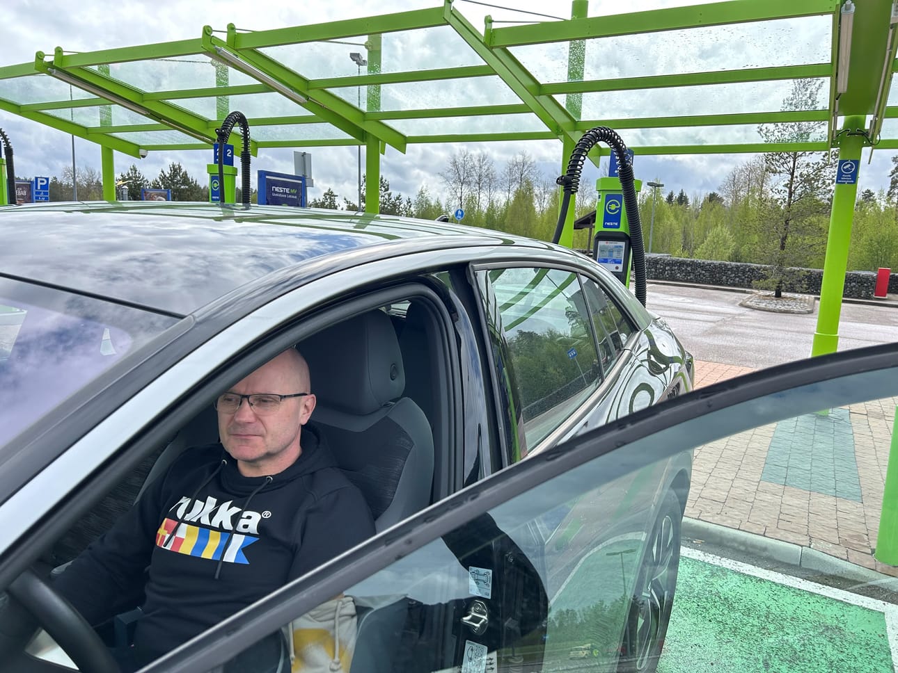 Toni Oksman istuu autossa sillä aikaa, kun akku täyttyy Neste Kivihovin liikenneasemalla. Kuva: Marjo Oikarinen