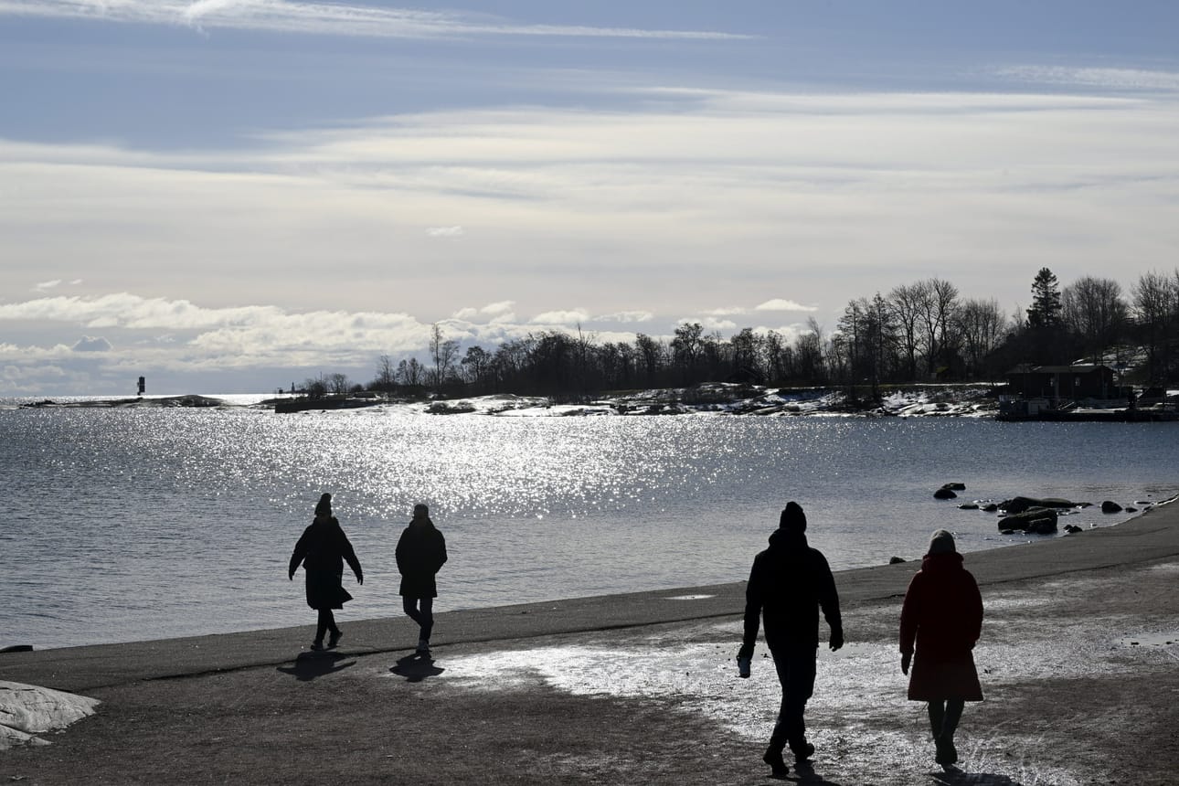 Ihmisiä meren äärellä Kaivopuistonrannassa Helsingissä aurinkoisena sunnuntaina 16. maaliskuuta 2025.