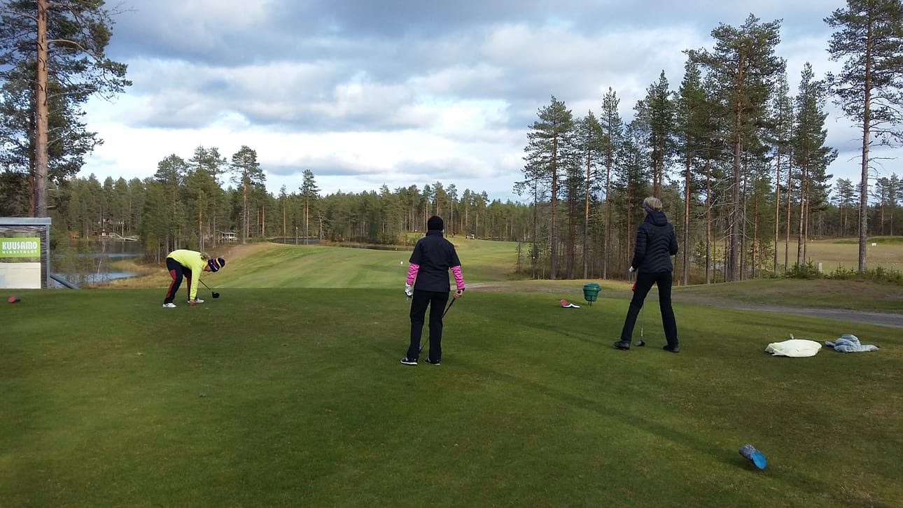 Väylän 10 punainen tee (avauslyönnin paikka) ja taustalla saman väylän greeni eli viheriö, jolla sijaitsee väylän reikä, johon pallo on tarkoitus saada mahdollisimman vähillä lyönneillä.