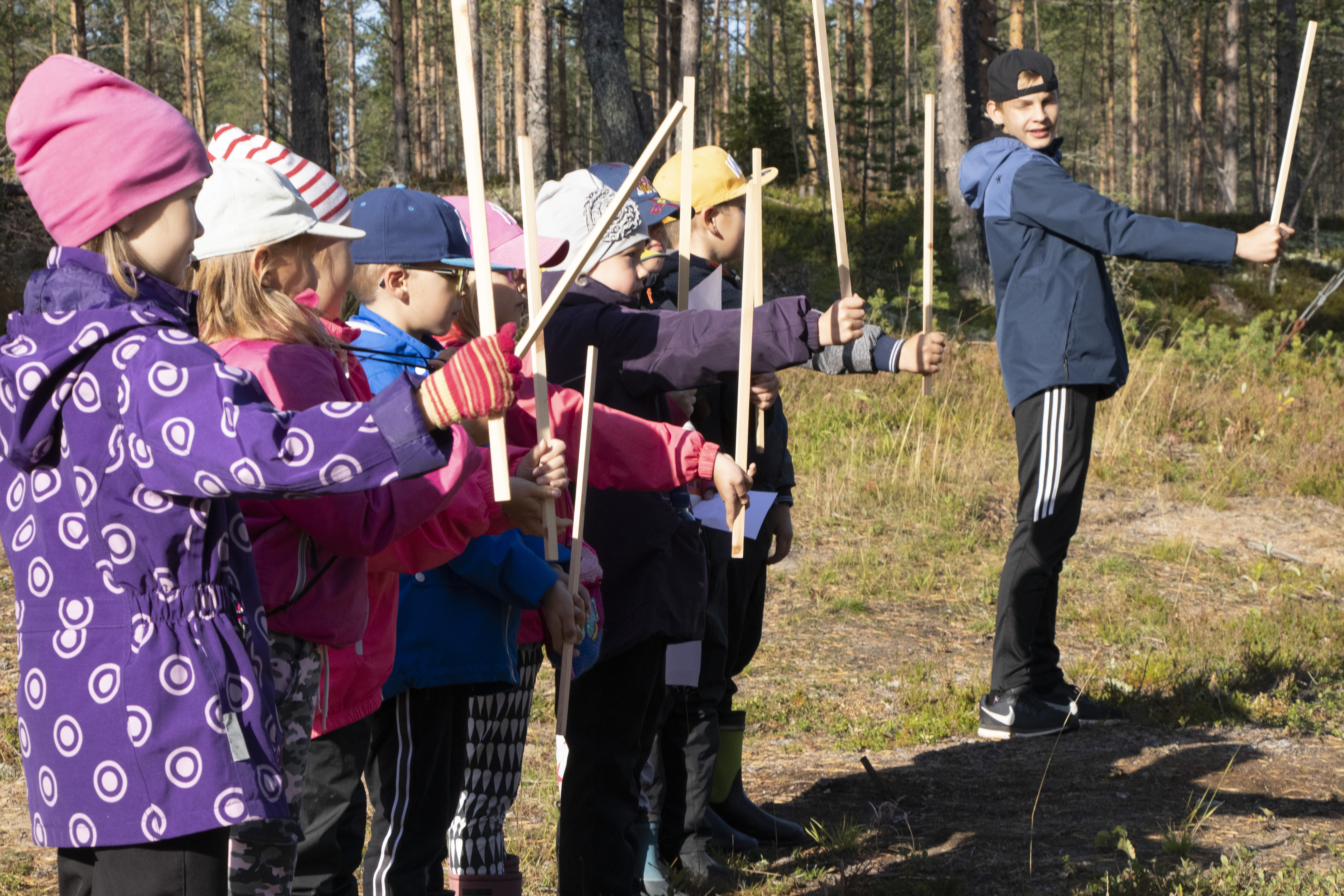 Toisen luokan oppilaita arvioimassa puun korkeutta. Opastamassa yhdeksäsluokkalainen Tuomas Haho (oikealla).