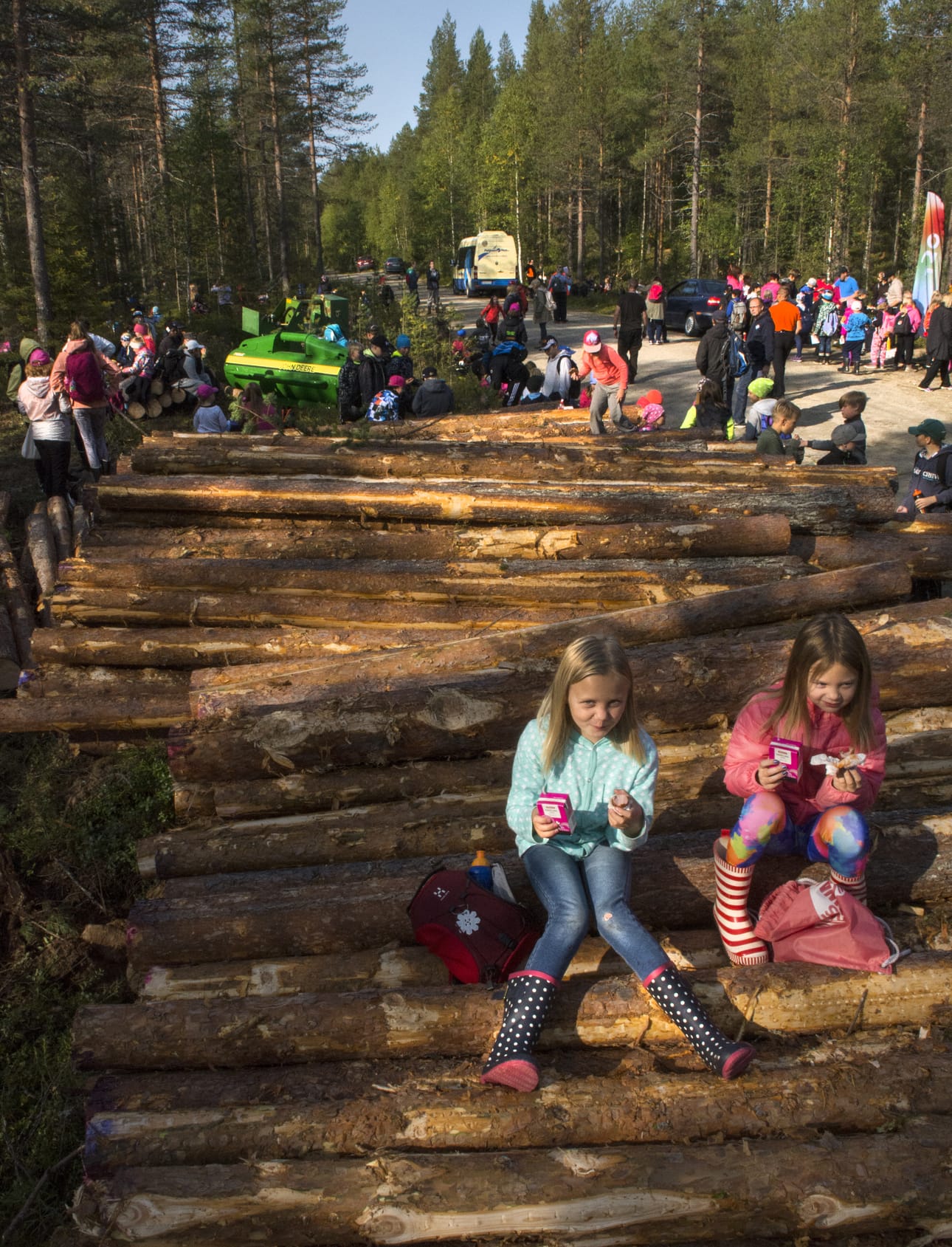 Milla ja Minttu nauttivat eväitä metsässä. Rehtori kiittää vapaaehtoisten järjestelyitä ja kuljetuksia.