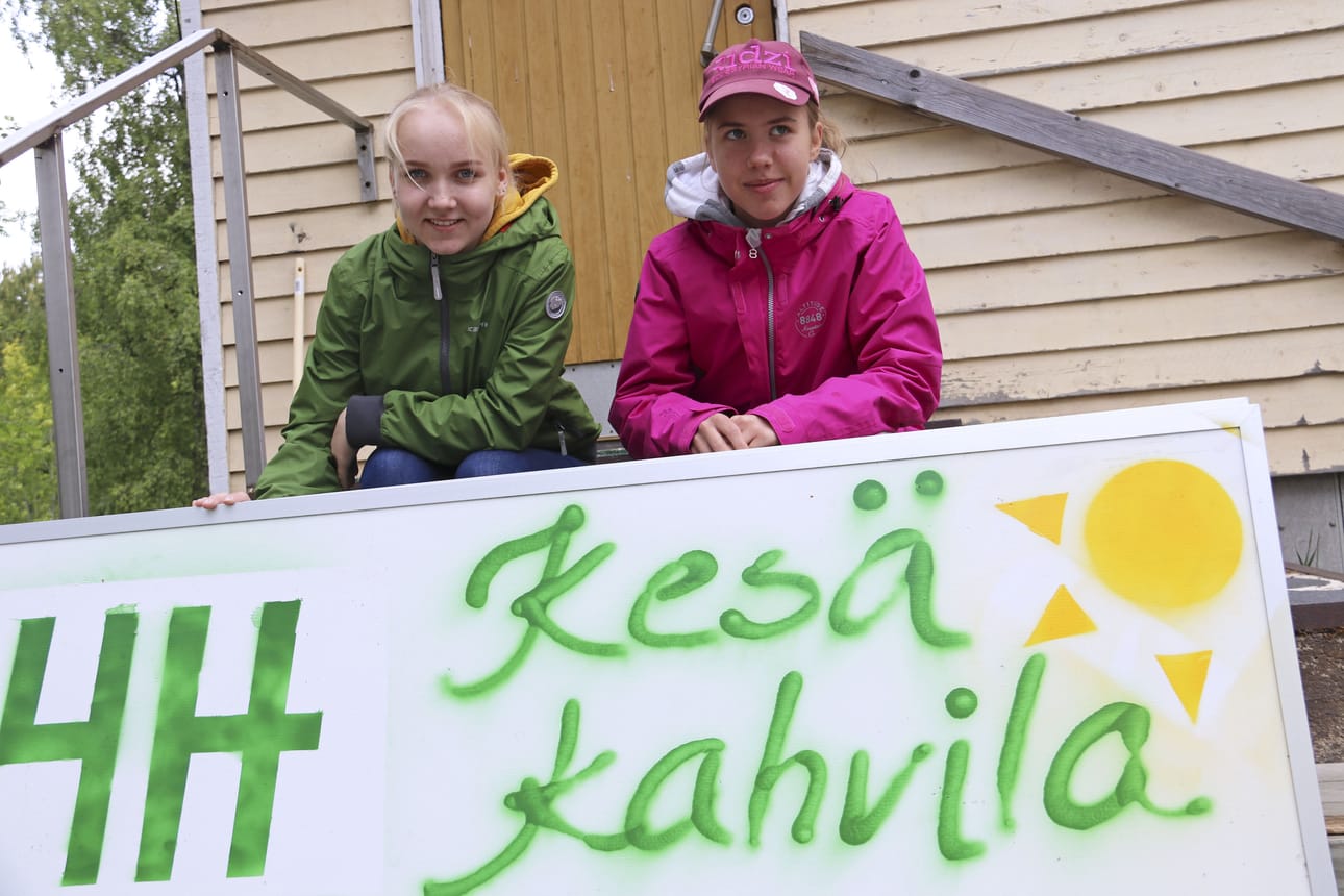 4H-nuorten kesäkahvila nojaa kierrätykseen. Opastekin on tuunattu vanhasta mainoskyltistä, kertovat Iida Taskinen (vasemmalla) ja Eveliina Ronkainen.