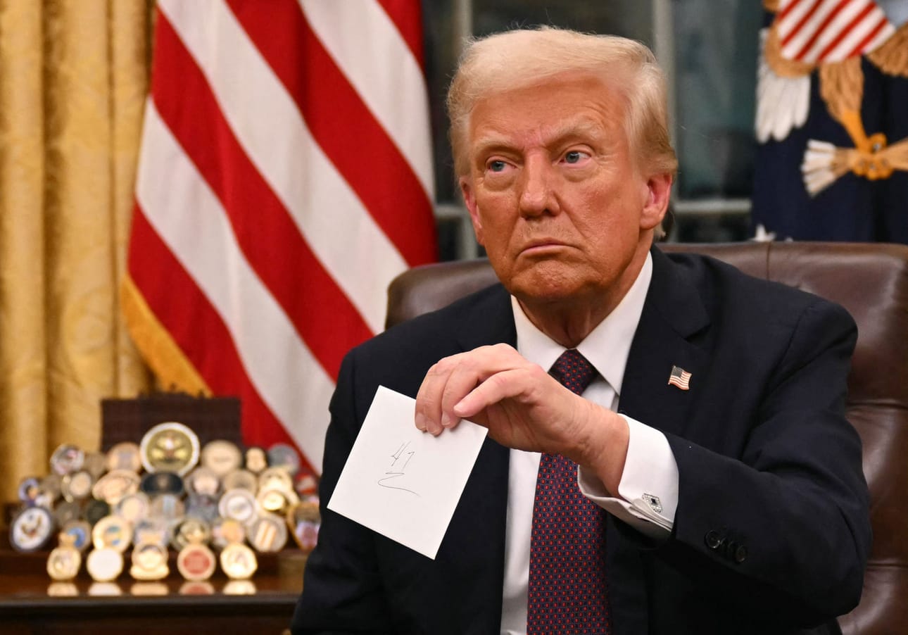 Presidentti Donald Trump piteli käsissään edeltäjänsä Joe Bidenin kirjettä ryhtyessään allekirjoittamaan presidentin asetuksia. LEHTIKUVA / AFP