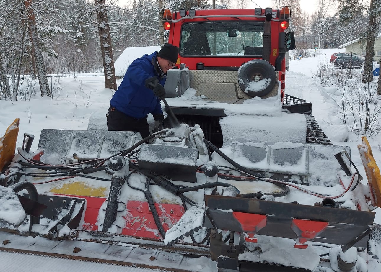 Hautamäki harjaa latukoneen irtolumesta reitin ajamisen jälkeen.