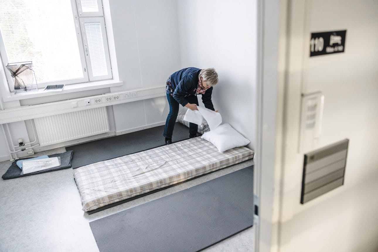 Vastaanottokeskuksen johtaja Ritva Metsälampi petaa malliksi lattialle sängyn. Hätämajoitukseen saapuvat yöpyvät siellä vain hetken.