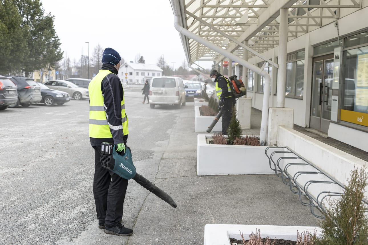ISS Palvelu Oy:n työntekijät puhdistivat hiekoitushiekkaa Kelan toimiston edustalla Kuusamon keskustassa lehtipuhaltimilla.