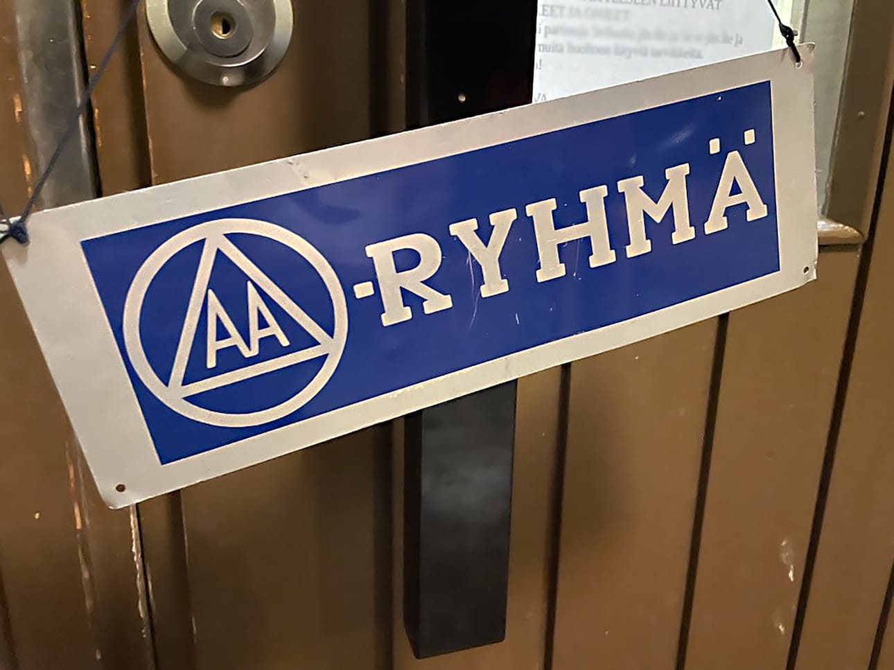 Tällaisen kyltin voit nähdä esimerkiksi Oulaisten Peltokartanon kokoustilan ovella keskiviikkoisin. Oven takana kokoontui tuolloin AA-ryhmä, jonne jokainen alkoholin aiheuttamien haasteiden kanssa kamppaileva on tervetullut kohtaamaan toisia, samankokeneita ja -kokevia henkilöitä.