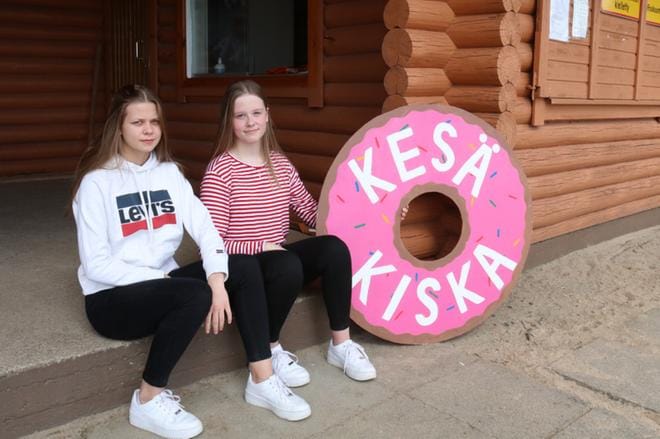 14-vuotiaat Emma Takamaa ja Siiri Luoma virittelivät perjantaina itse tekemiään kylttejä kioskin seiniin. Sunnuntaina olivat avajaiset. KUVA: ANU NAHKALA