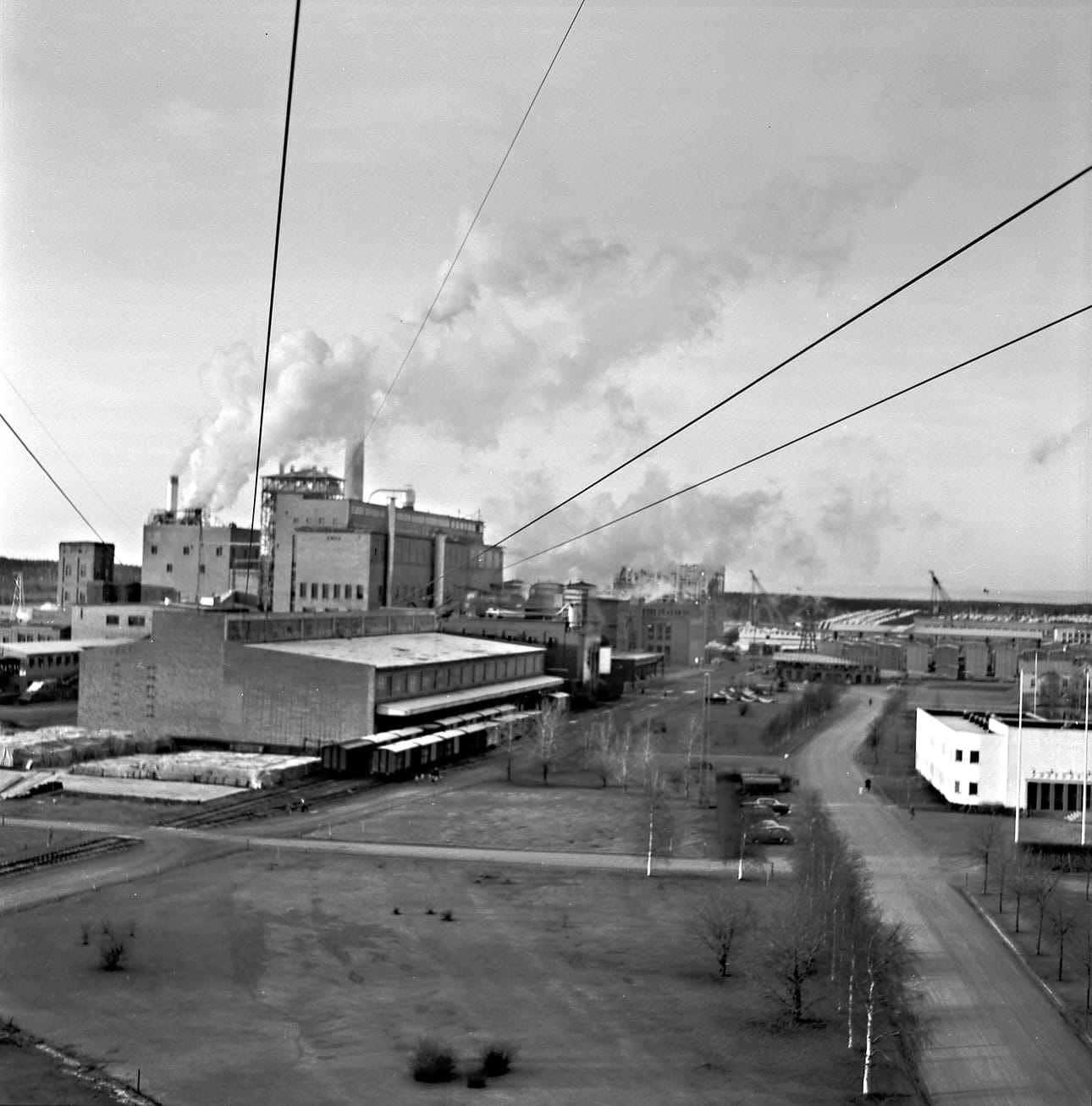 Kajaani Oy:n tehdasaluetta Kajaanin Tihisenniemellä marraskuussa 1958 Veikko Aitoahon kuvaamana. Vasemmalla paperi- ja sellutehtaat, takana yhtiön sahan aluetta ja oikealla pääkonttori. Aitoaho kuvasi kajaanilaista maisemaa niin filmille kuin valokuviksikin. Kuva on Kainuun museon kuva-arkistosta.