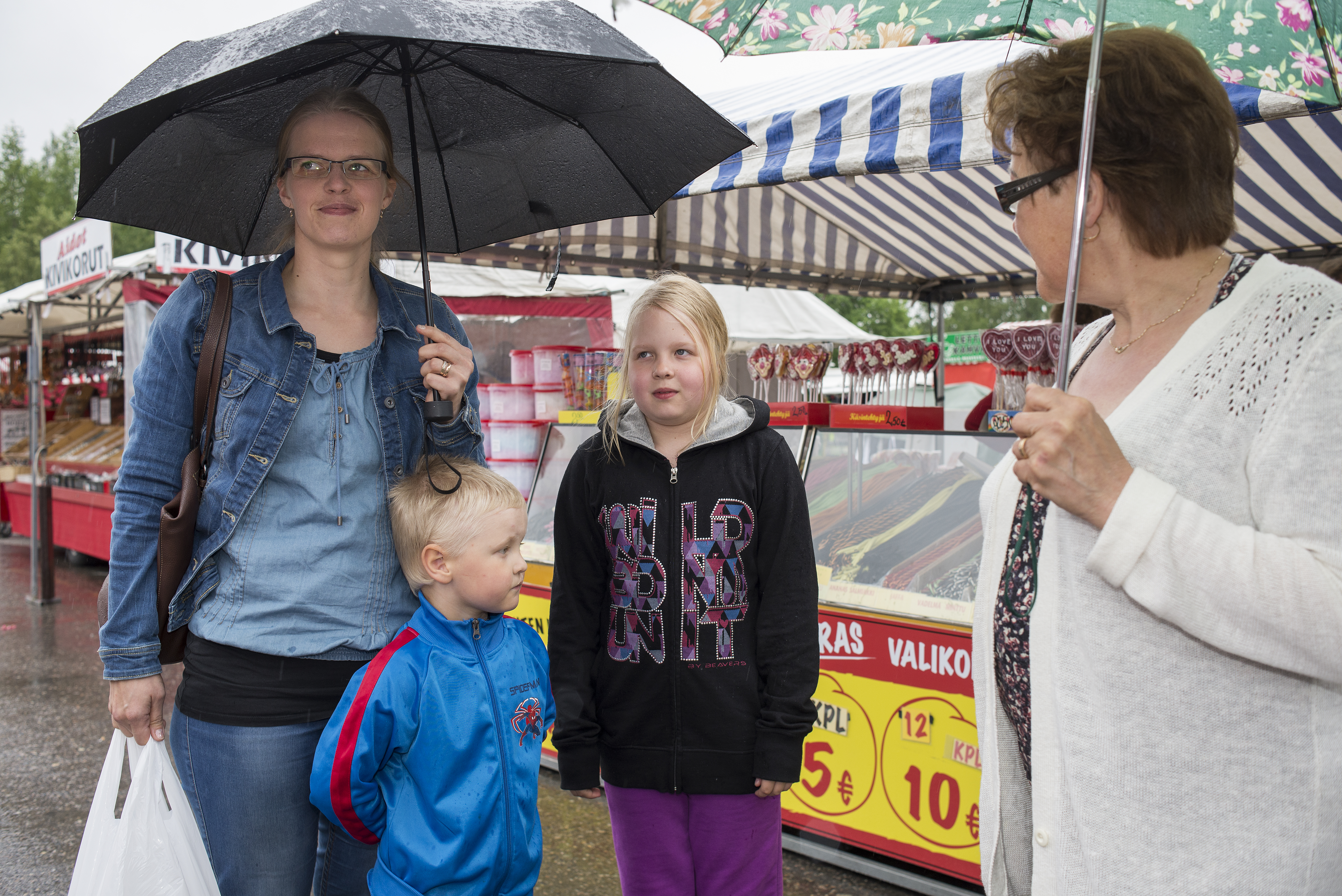 Sateenvarjoilla suojautuneet Mari, Juho ja Jenna Rouhiainen sekä Arja Jaatinen tulivat käymään markkinoilla mökiltään Vuotungista.