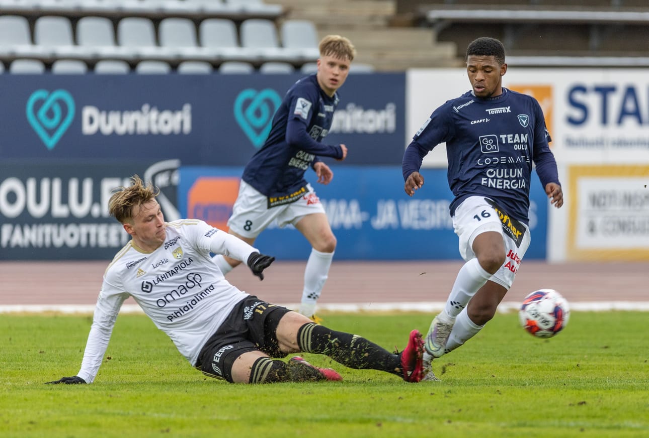 SJK:n oululaispelaaja Ville Tikkanen taklaa AC Oulun keskikenttäpelaajaa Yanga Balisoa.