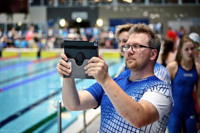 Valmentajan arkipäivää altaan reunaalla: valmentajan ammattitutkintoa opiskeleva Kalle Lydman videoi uimareidensa suoritukset. KUVA: TOMI KOSONEN