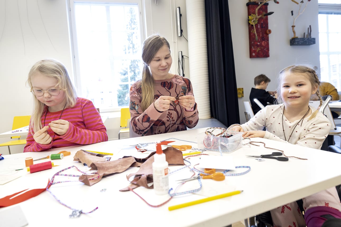 Eila Kyllönen (vas), Tuuli Viholainen ja Siiri Viholainen tekevät Oulun taidemuseon perhepäivän työpajassa avaimenperiä materiaaleista, joita käytetään saamelaisissa käsitöissä.