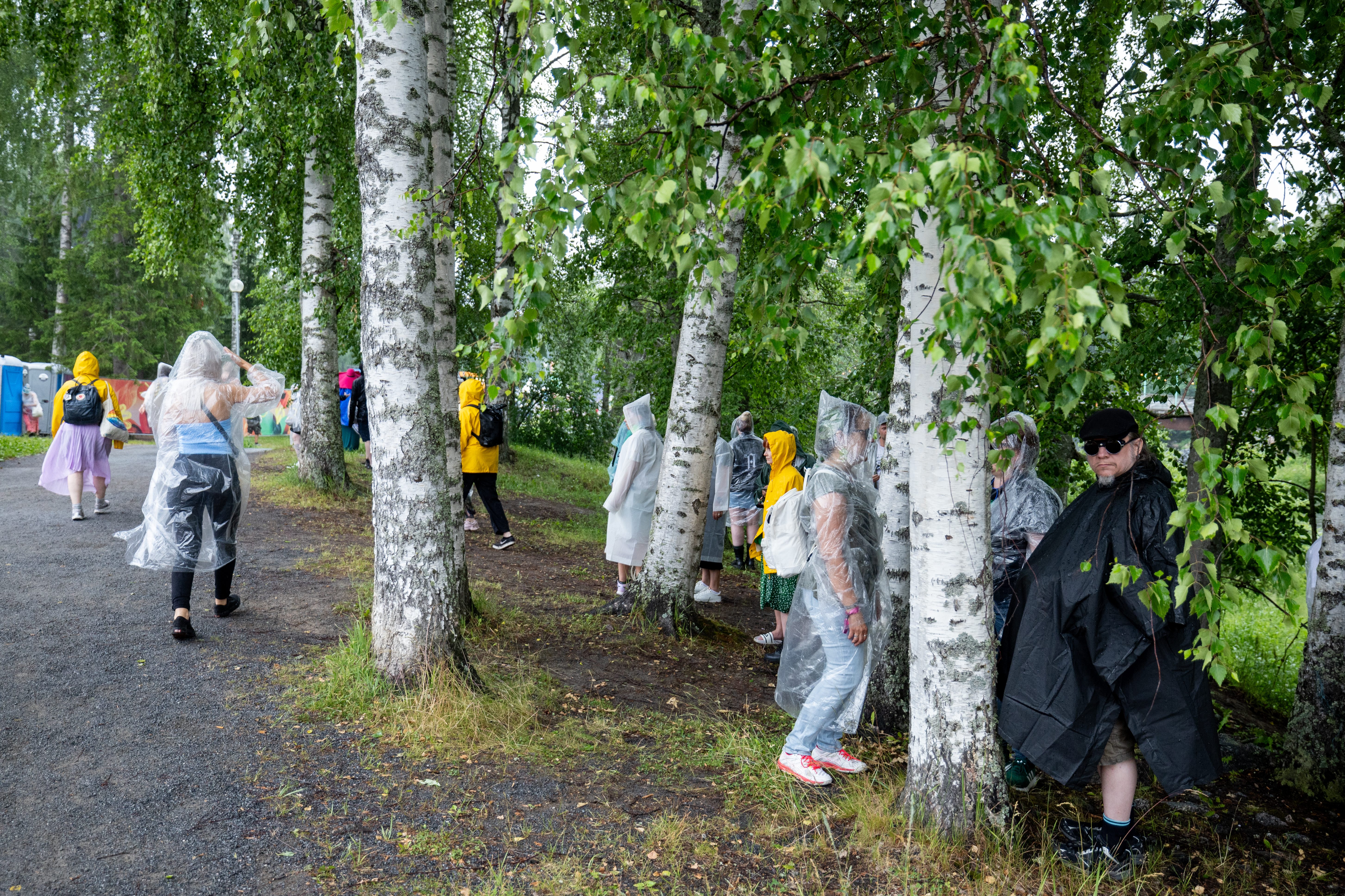 Katokset täyttyivät nopeasti, joten festivaalivieraat hakivat sateelta suojaa puiden alta.