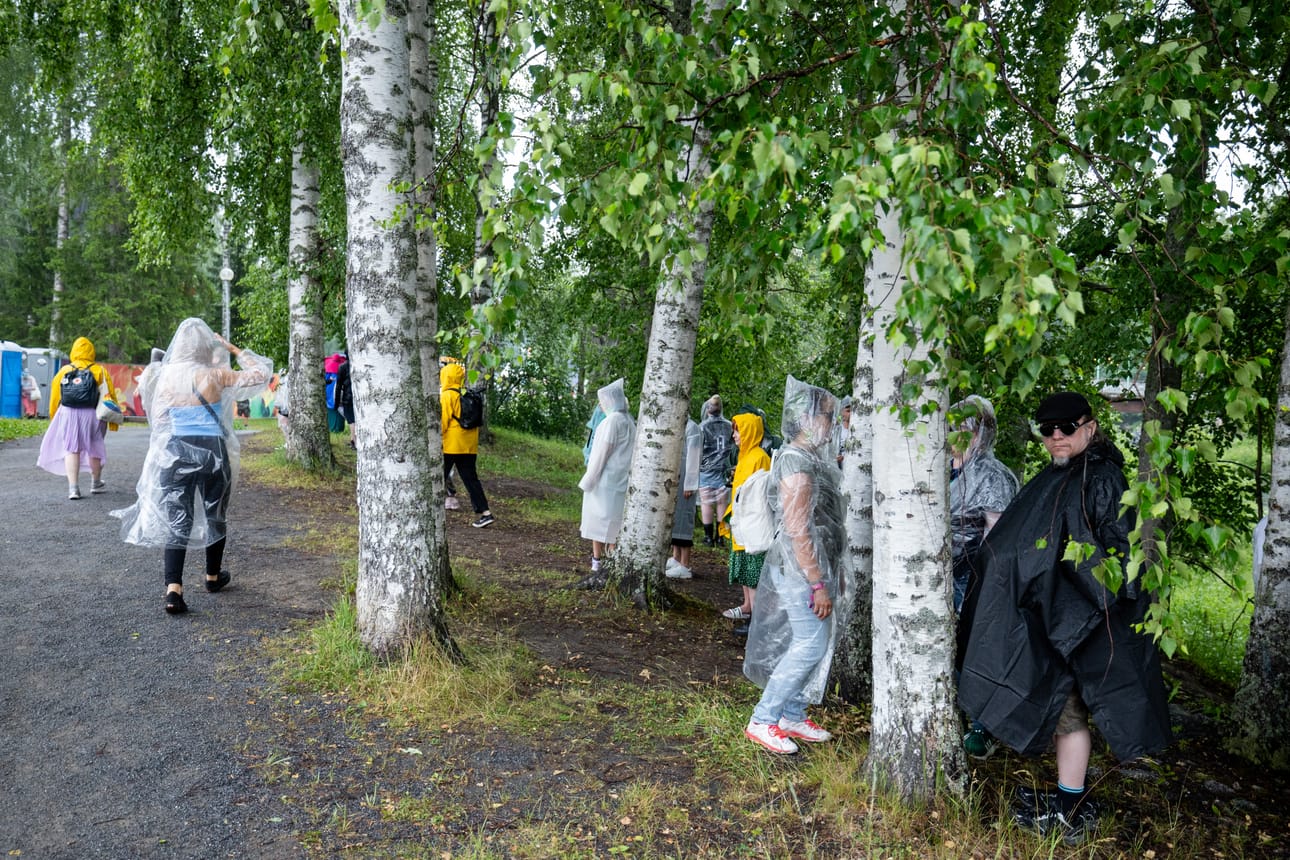 Katokset täyttyivät nopeasti, joten festivaalivieraat hakivat sateelta suojaa puiden alta.