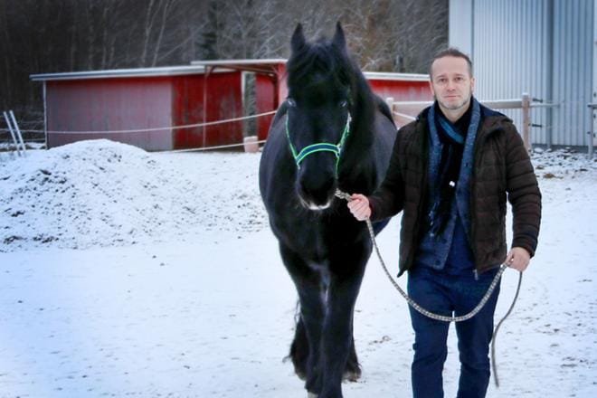 Osku Ketola rentoutuu hevostallilla. Miehen oma hevonen on rodultaan friisiläinen ja nimeltään Leo. Kuva Virpi Kupiainen-Ämmälä