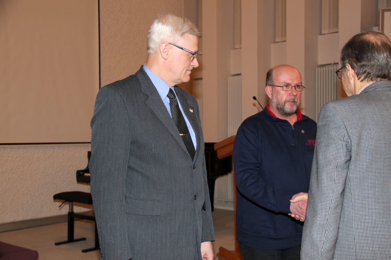 Kuvassa puheenjohtaja Paavo Pikkuaho onnittelee Juha Hagelbergiä, vieressä Jukka Lehto. Kolmas Pohjois-Pohjanmaan Sotaveteraanipiirin myöntämän hopeisen ansiomerkin saanut Heino Ruuskanen ei päässyt paikalle.
