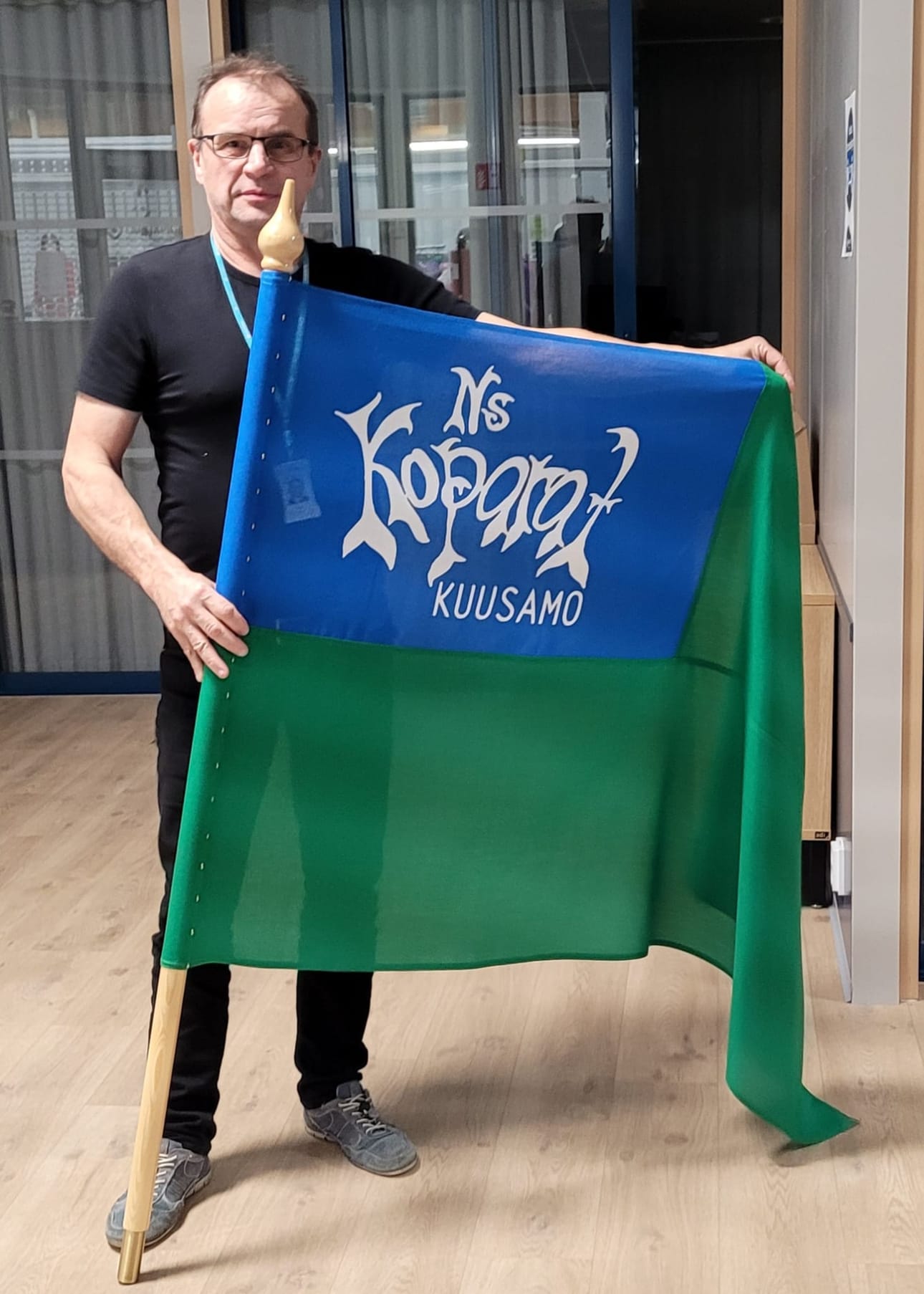Timo Nissi ja Nuorisoseura Koparoiden lippu, jonka kirjaimista voi löytää Kuusamon vaakunaeläimen sarvia ja koparoita eli sorkkia.