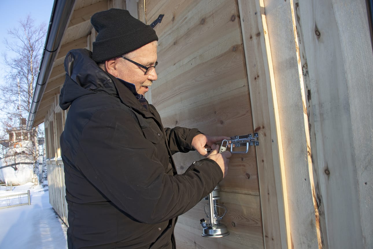 Kyläyhdistys toivoo rakennuksen säästyvän ilkivallalta. Juha Korkala ovea lukitsemassa.