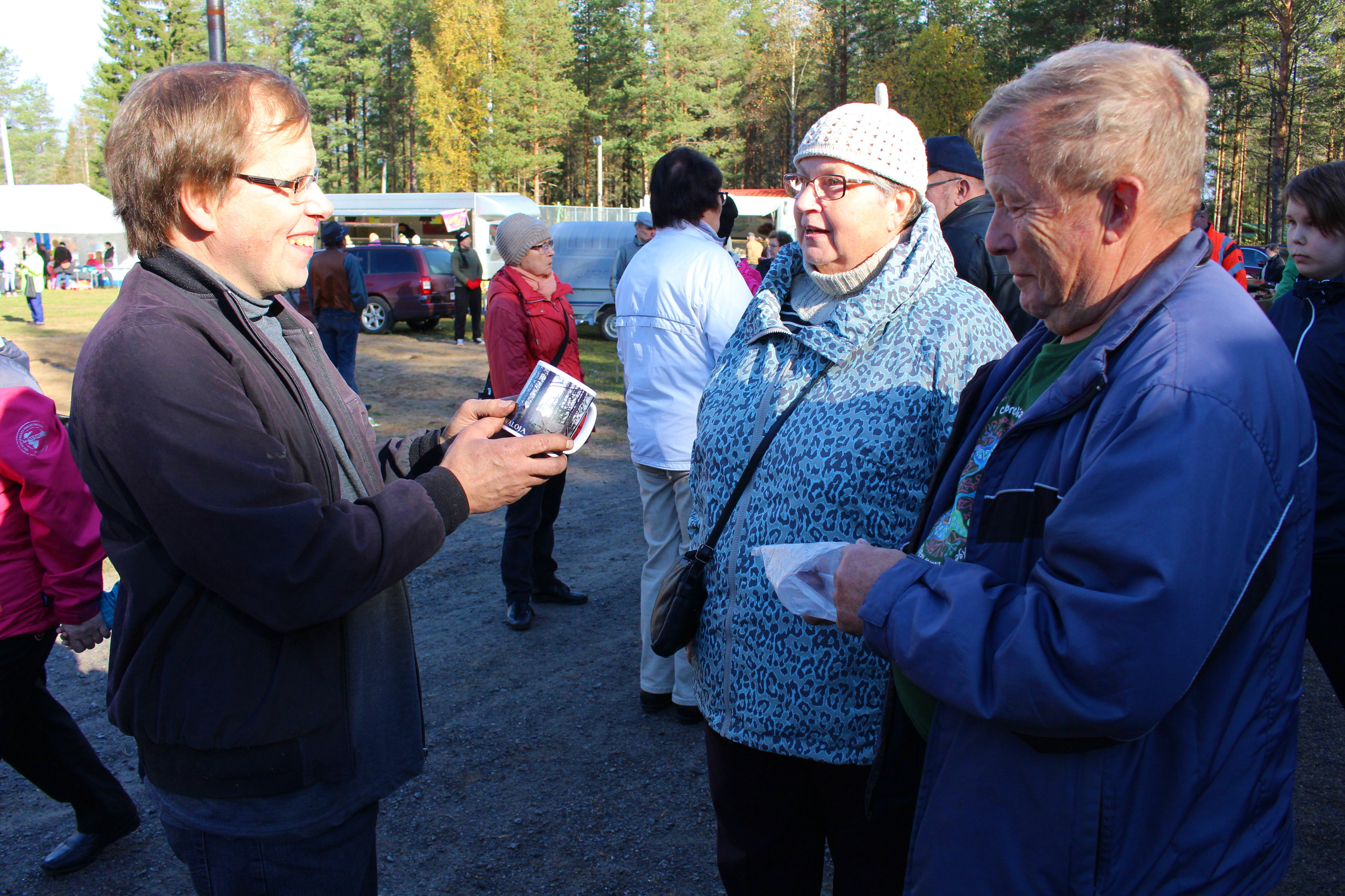 Syysmarkkinat kokosivat entisiä kyläläisiä Hovin koululle. Mykylän sisarukset: Savalojalla asuva Jarmo, Kempeleessä asuva Laura Vuoti ja Sipolassa asuva Kari ihastelivat juuri julkaistua mukia. Kotitalon kuoppakin oli ikuistettu mukiin.