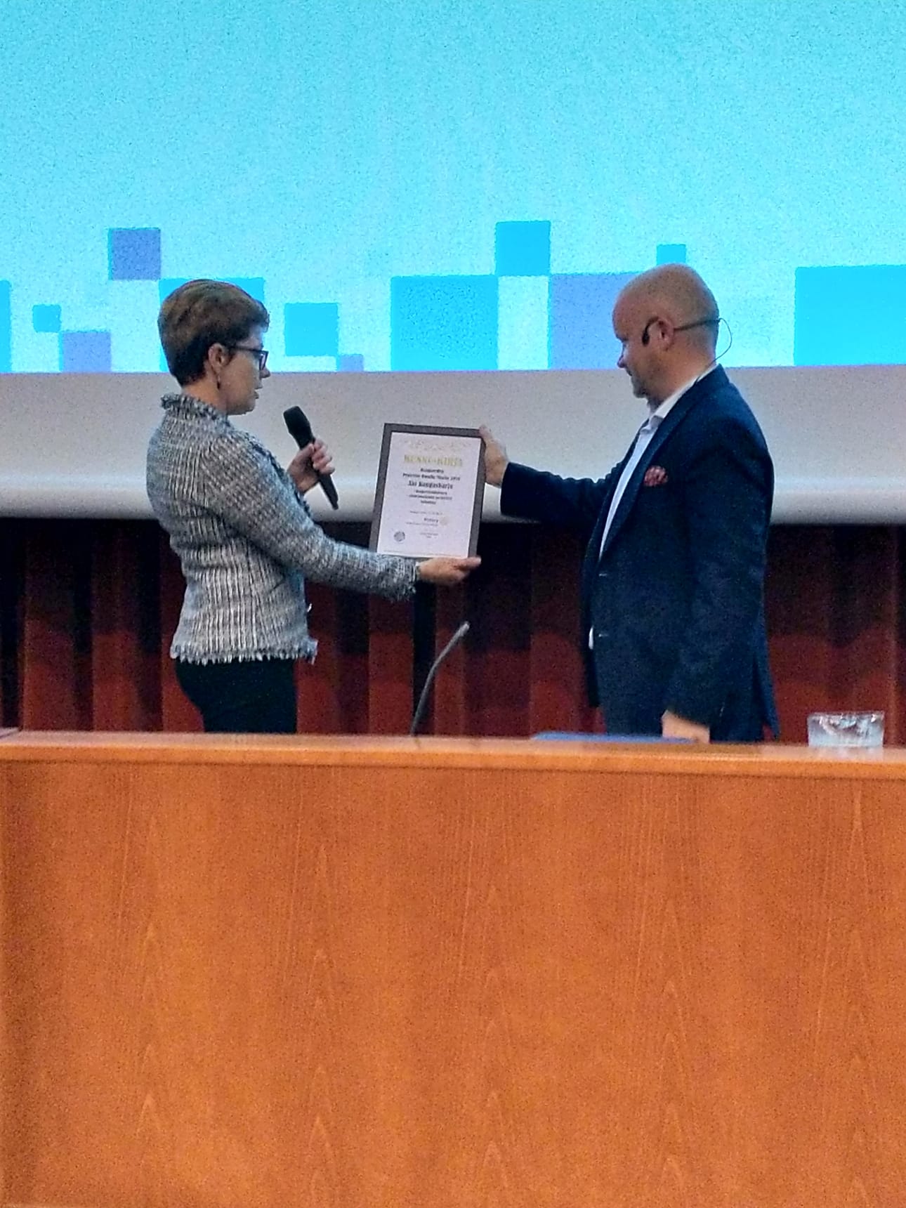 Kunniakirjaa Aki Kangasharjulle ojentamassa Haapaveden Rotaryklubin presidentti Seija Mäkinen.