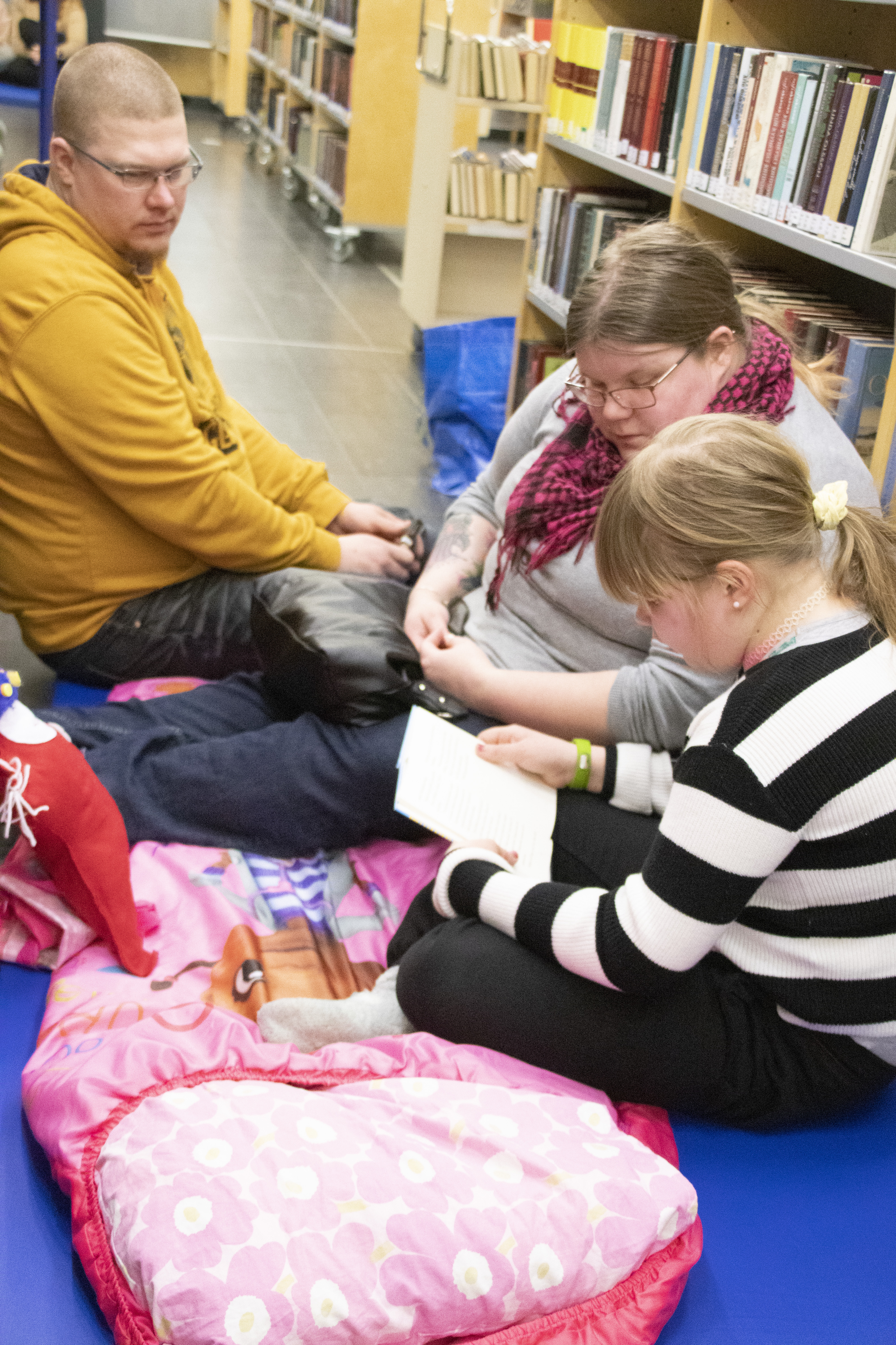 Kirjastoyöhön oli varustauduttu omilla petivaatteilla. ? oli mukana soma makuupussi. Iltasatua kuulemassa vanhemmat.