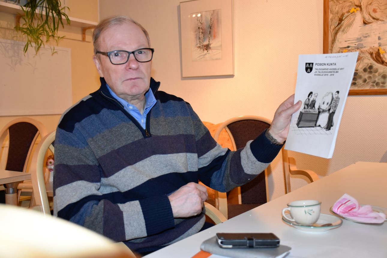 Kunnanhallituksen puheenjohtaja Olavi Lehtiniemi pitelee kädessään budjettikirjaa, jossa vuoteen 2019 tehdyt laskelmat näyttävät kunnan talouden olevan tervehtymään päin.
