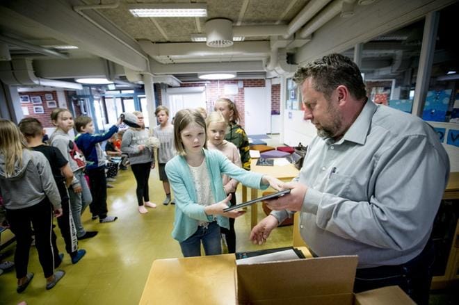 Tiistenjoen koulun oppilas Vilma Mäenpää sai keskiviikkona Jussi Lähteeltä ensimmäistä kertaa käteensä koulun oppilaiden työstämän kirjan. KUVAT: JAAKKO ELENIUS
