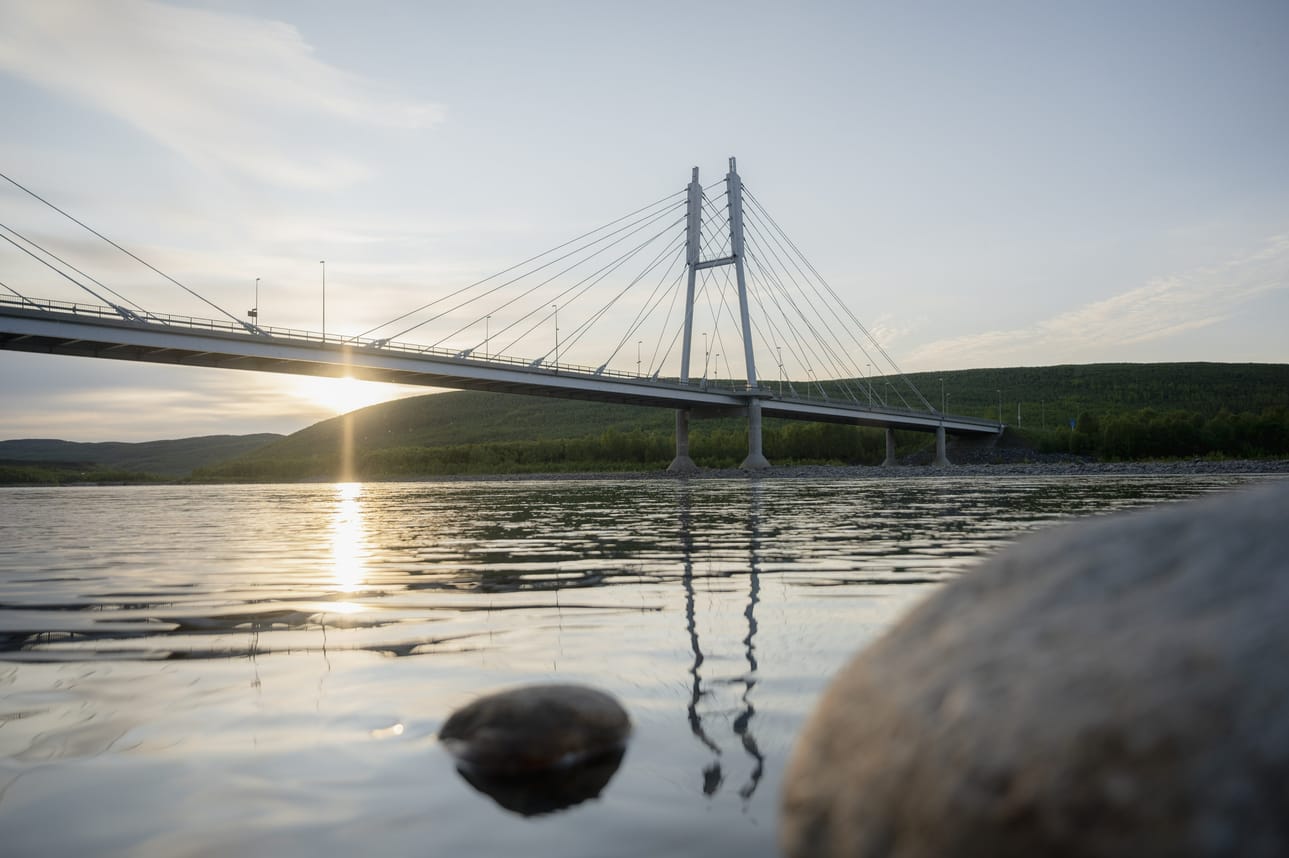 Aurinko paistaa yöllä Tenojoen yllä Suomen ja Norjan rajalla.