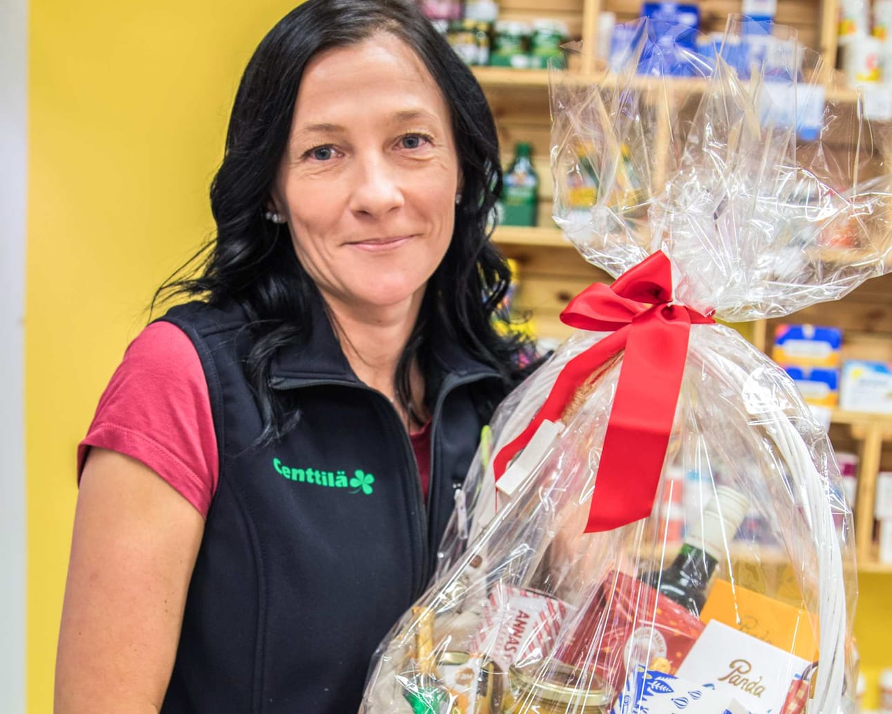 Soile Alamäki tuo takahuoneesta läpinäkyvällä lahjamuovilla paketoidun valkoisen korin, jossa on sisällä erilaisia joulutuotteita. Löytyy suklaata, hilloja, mausteita, teetä, lasinen glögipullo ja kynttilöitä. Centtilä on rakentanut lahjakoreja jo muutaman vuoden ajan ja tänä vuonna niitä voi jälleen nähdä liikkeessä. ”Voimme räätälöidä korin asiakkaan toivomusten mukaan.”