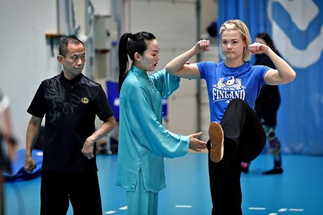 Chen Jing näytti oppilaansa Jaana Meriläisen avulla raajojen oikean kulman. Valmentajan ohjeet käänsi kiinasta englanniksi foorumin isäntä Zhang Fang (vasemmalla) Suomen Wushu-liiton terveys-qigong-jaostosta.