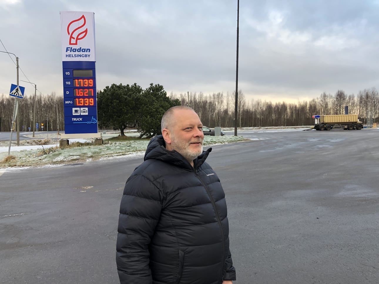 Huoltamopäällikkö Kenneth Back esittelee uudelleen nimettyä polttoainetolppaa. Fladan-nimen taakse ovat jääneet Teboilin ja Lukoilin tekstit.