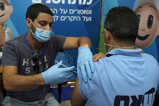 Terveydenhuollon työntekijä antaa asiakkaalle kolmannen annoksen Pfizer-Biontechin koronarokotetta Clalitin terveysasemalla Jerusalemissa. Kuva: Menahem Kahana/Lehtikuva
