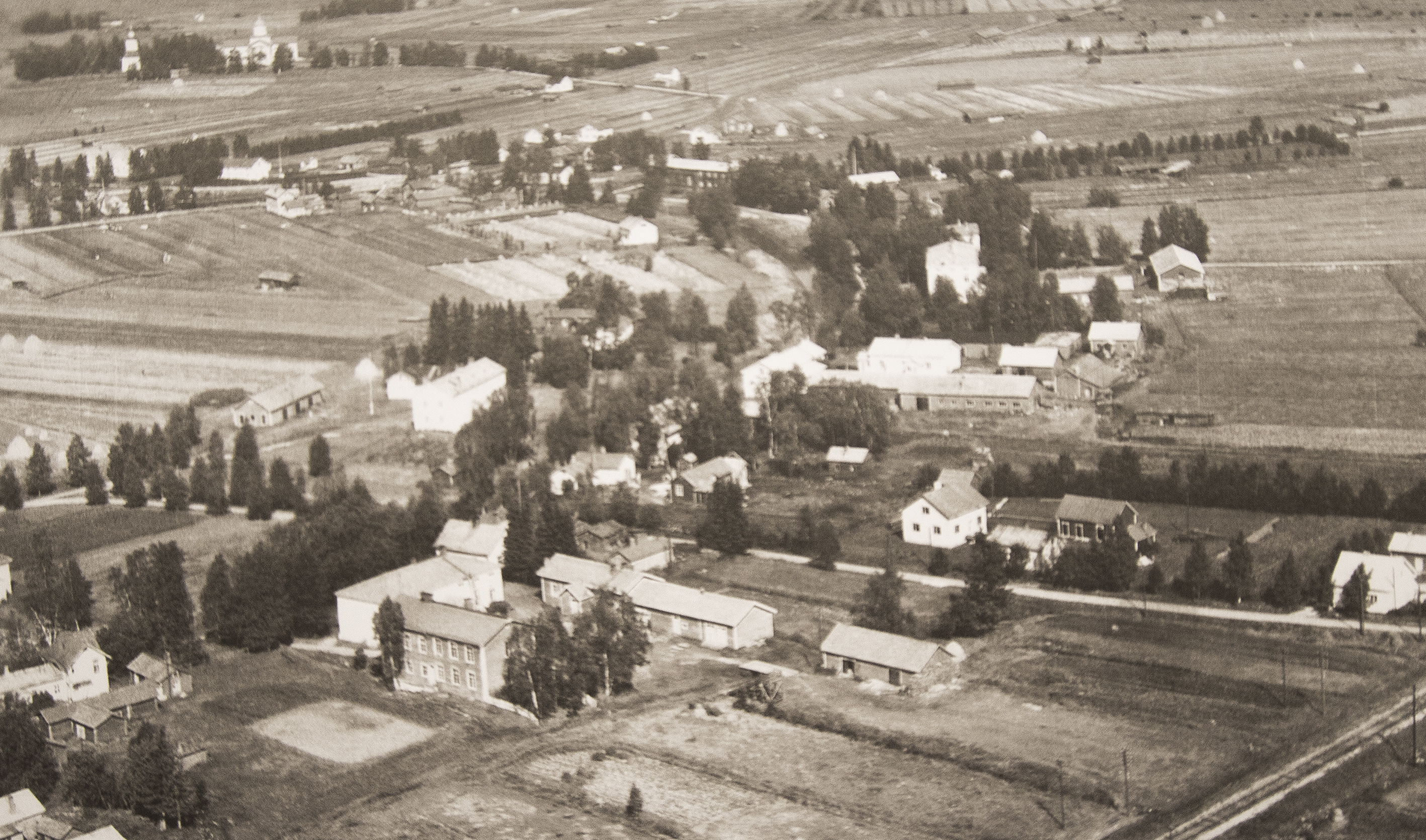 <p>Nykyinen museoalue näkyy vanhassa ilmakuvassa keskellä alhaalla. Rakennuksista on jäljellä kivikoulu ja vasemmalla puolella olevat Aappolan rakennukset. </p>