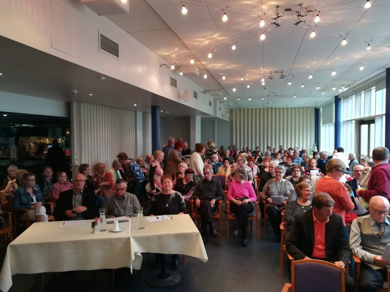 Kilpailun yleisöä, kilpailijoita ja tuomaristo Eero Nevala, Alla Kouru ja Rauno Uusitalo (edessä istuvat pöydässä).