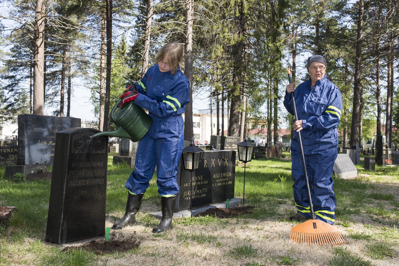 Mirjami Kämäräinen pesee hautakiveä, kun Irmeli Ollila viimeistelee haudan pintaa. Irmeli Ollila työskentelee seitsemättä kesää hautausmaalla.
