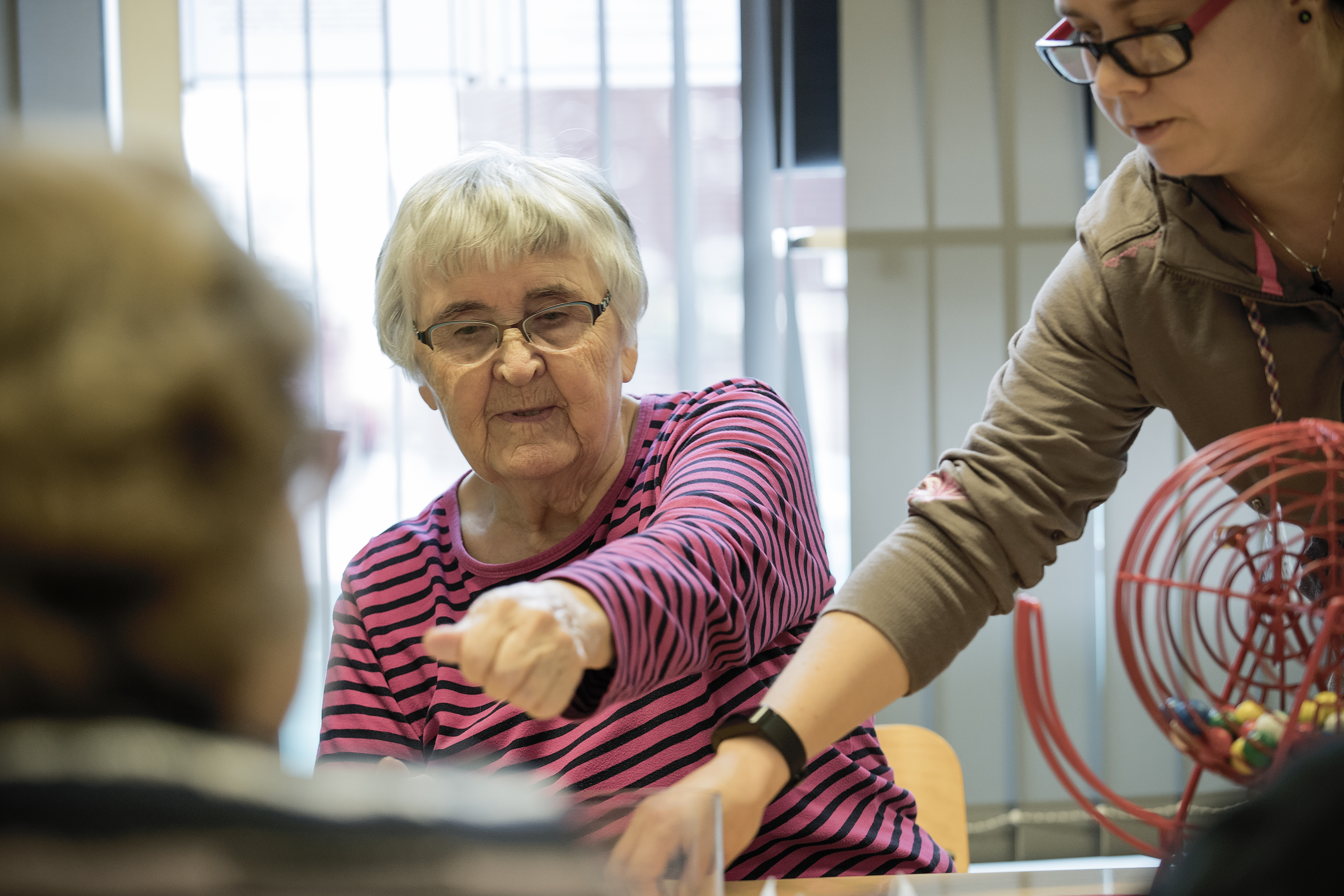 Kerttu Andersson saa bingon, kun Hanna-Mari Vikstedt pyörittää bingopallokonetta.