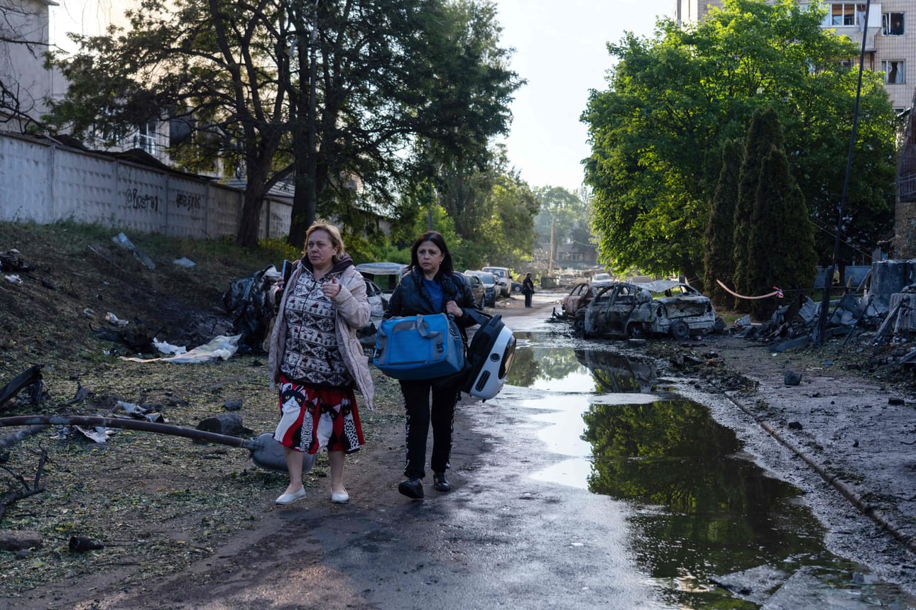 Paikalliset asukkaat kantavat tavaroitaan kävellessään tuhoutuneiden autojen ja raunioiden ohi varhain tiistaiaamuna. Venäjä pommitti Ukrainaa sadoilla droneilla ja kymmenillä ohjuksilla surmaten ainakin 11 ihmistä.