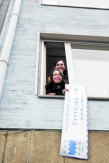 Eija Pietilä (alh.) ja Tiina Rödlin kiinnittävät nimitarran Tyttöjen talon iukkunaan Rotuaarilla.