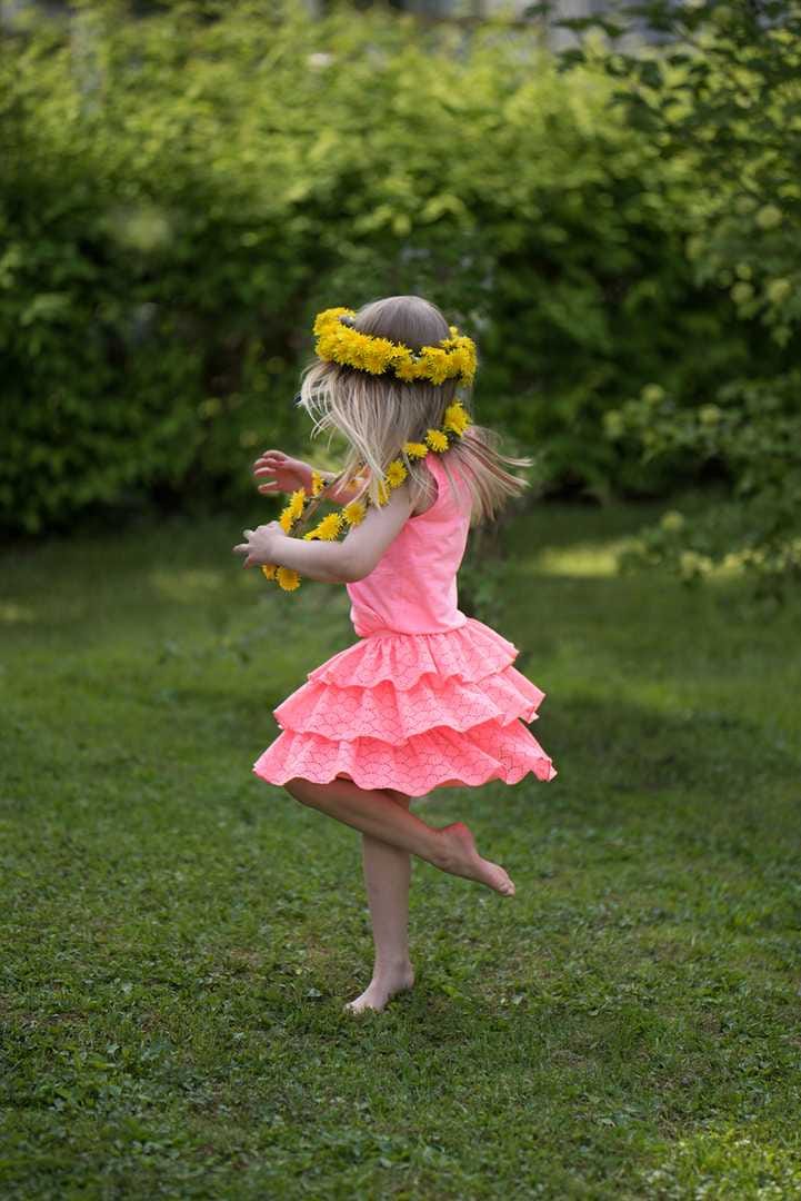 Kesän tyttö. Iloinen kesätyttö Alina tanssii mummolansa pihanurmella Kairatiellä.