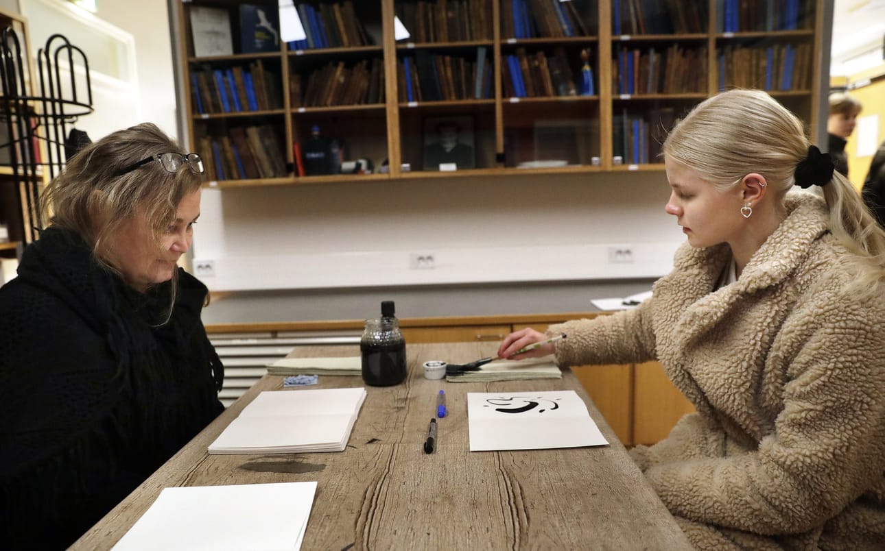 Muhoksen lukion oppilas Jenni Inkala (oik.) maalasi musteella Mari Liimataisen Tahroja-teoksessa.