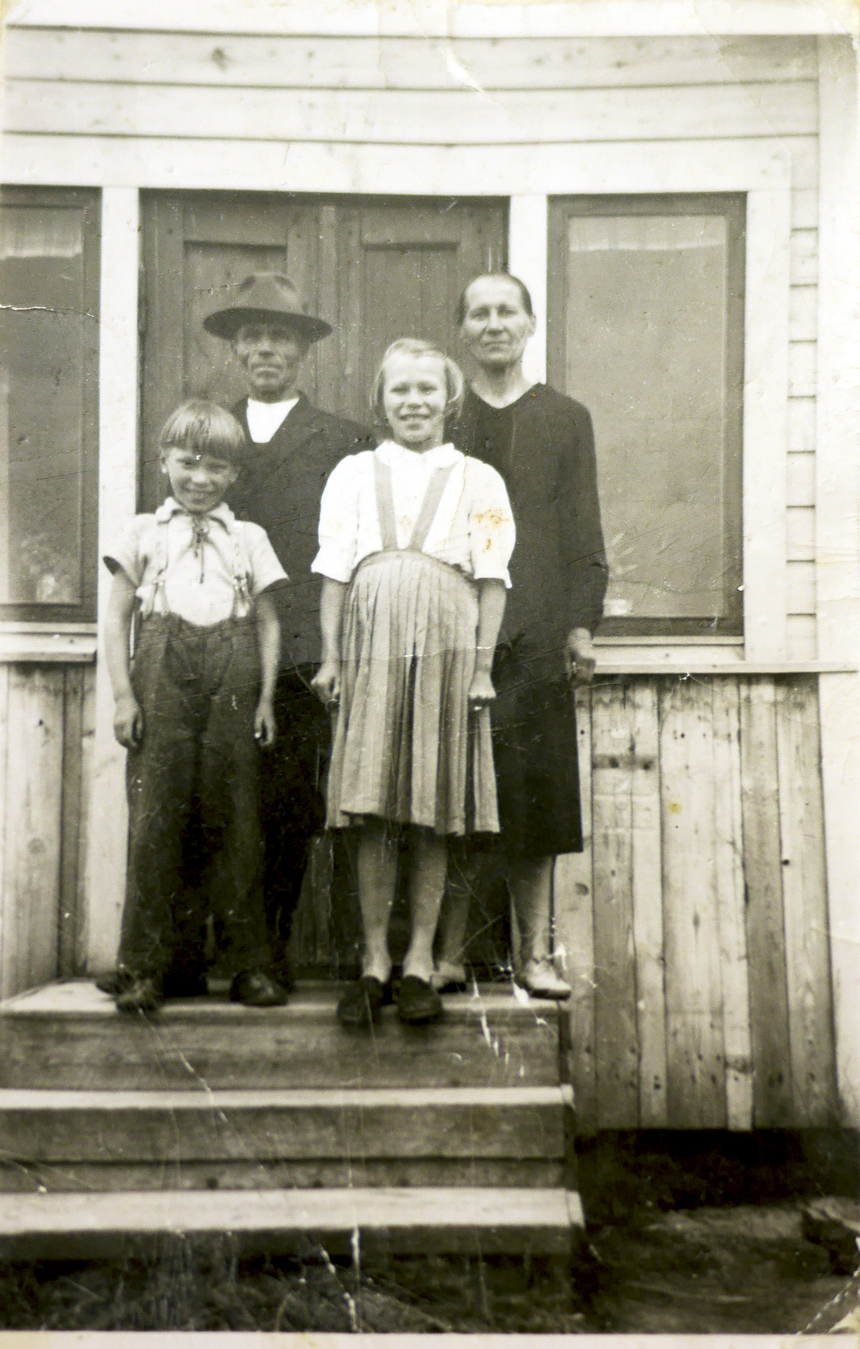 Kuva 1. Simo ja Iida Kovala tyttärensä Kyllikin ja poikansa Osmon kanssa kotitalonsa Pökkelöniemen portailla 1950-luvun puolivälissä.  (Kyllikki Riekin kokoelma)