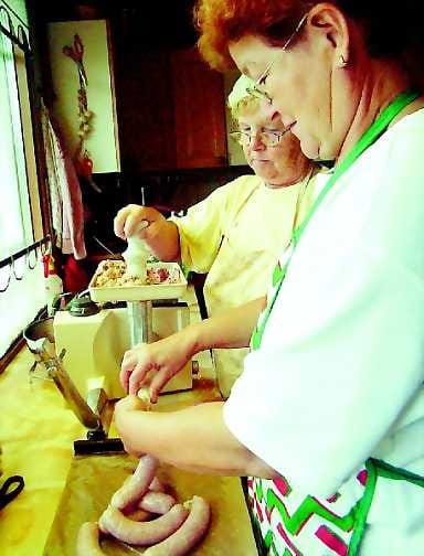 Taikina suoleen . Lea Lehtovuori (edessä) ja Riitta Meriläinen pursottavat makkarataikinaa luonnonsuoleen. Sopivan pituiset makkarat saadaan, kun pötköä kierretään muutama kierros niin, että jää tyhjä väli.