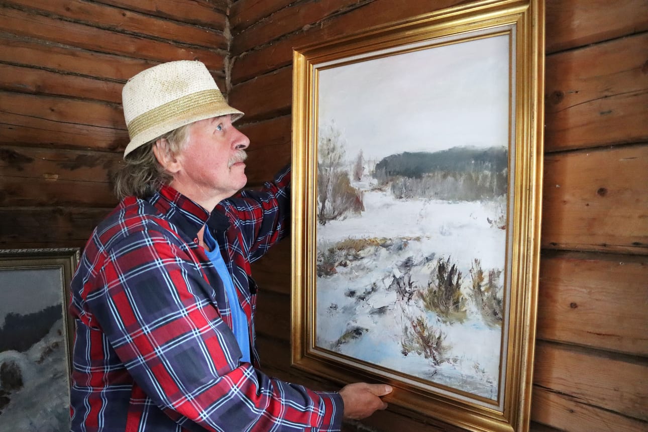 Aulis Uusi-Hakimo ripustaa öljyvärimaalaustaan Kummitustalon seinälle.