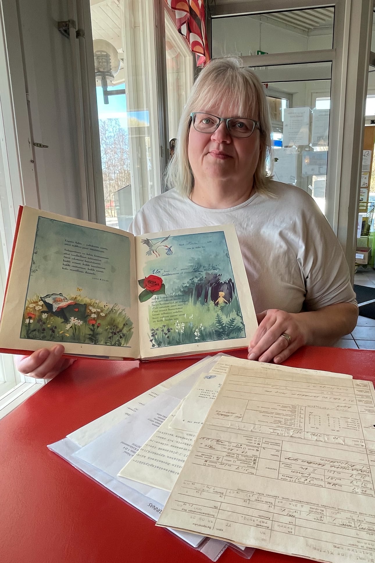 Marjo Nahkalan vauvakirja ja paperit, joista selviää Nahkalan adoptioprosessin vaiheet.