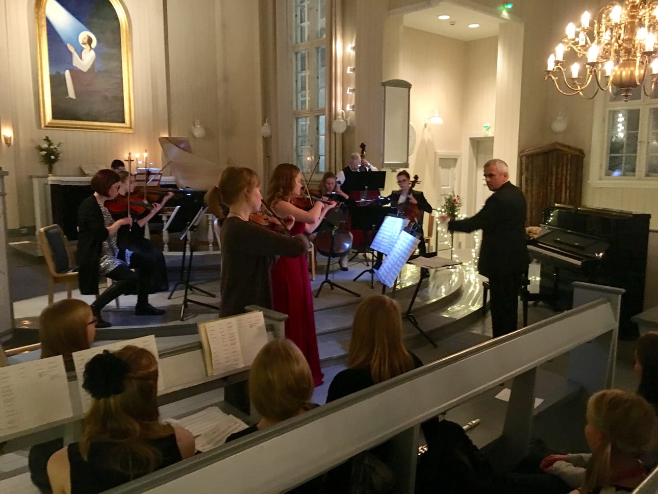 Vivaldin konserton esitys - solistit keskellä Siiri Janhunen ja Emilia Tyni, viulu Marek vas, johtamassa.